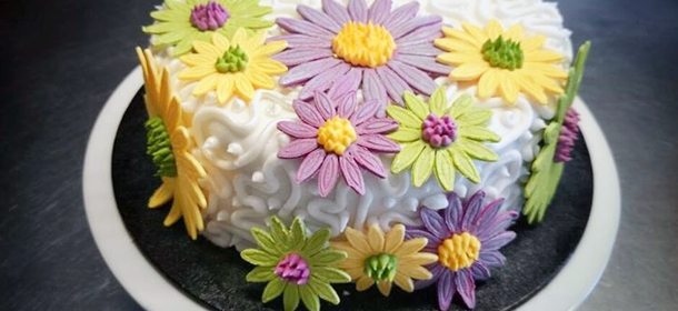 a white cake covered in colourful flowers 