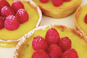 custard pastries with raspberries on the top 